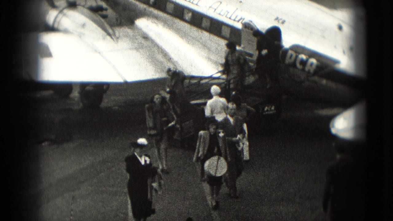 1975 Washington DC home-movie frame showing passengers leaving a passenger aircraft by mobile stairs on the tarmac.