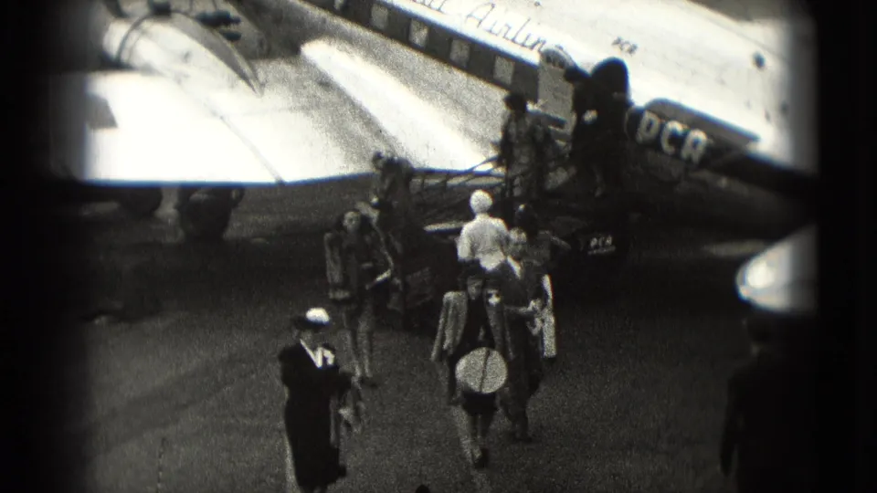 1975 Washington DC home-movie frame showing passengers leaving a passenger aircraft by mobile stairs on the tarmac.