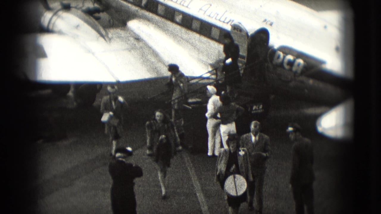 Passengers walk across the tarmac after leaving an aircraft with visible airline markings.