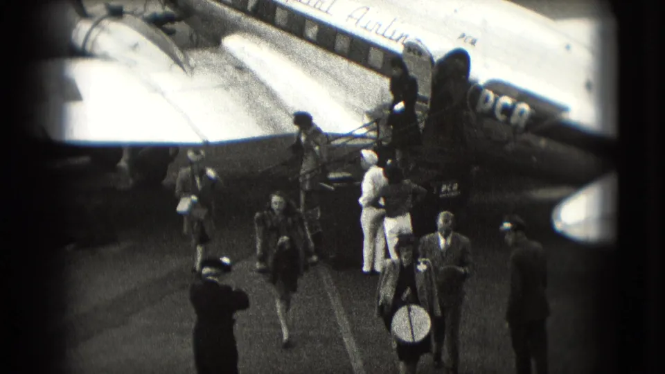 1975 Washington DC tarmac scene with travelers carrying bags after disembarking from a marked aircraft.