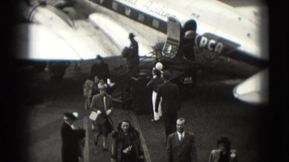 1975 Washington DC airport home-movie frame showing travelers walking from a marked aircraft after landing.