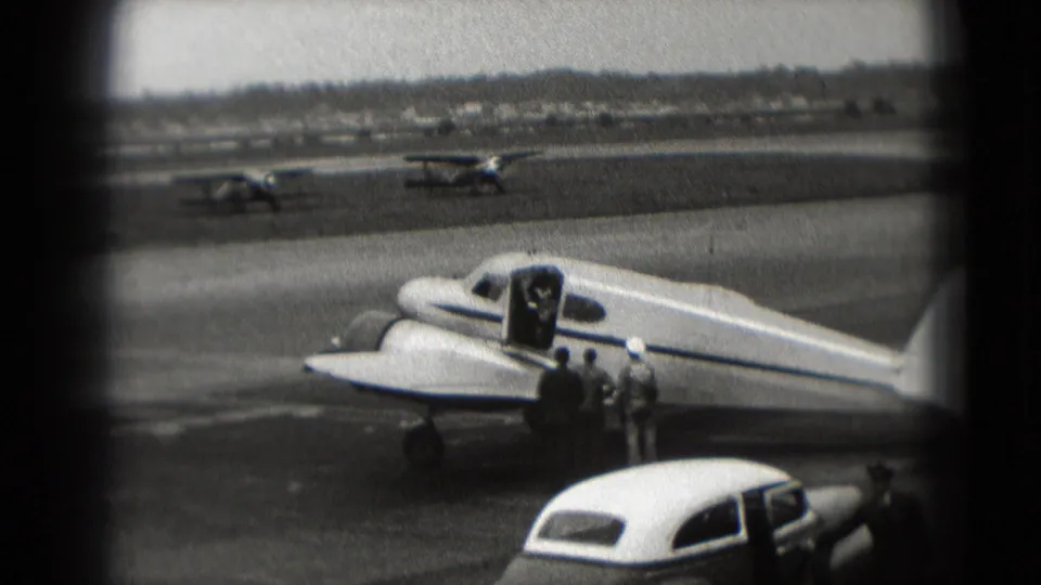 People stand beside an open aircraft door on a small propeller plane at a Washington, DC airport in 1975.
