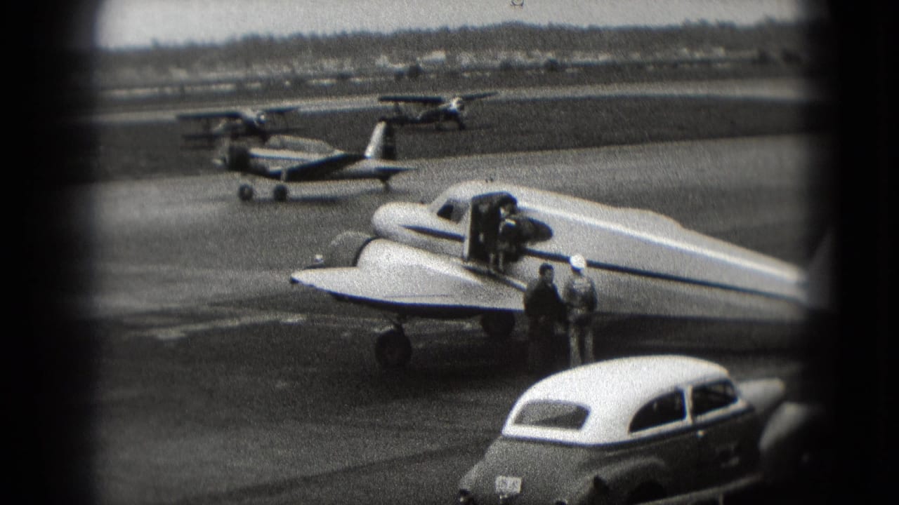 1975 Washington, DC tarmac view with a small propeller plane, adults near the wing, classic cars, and light aircraft in the background.