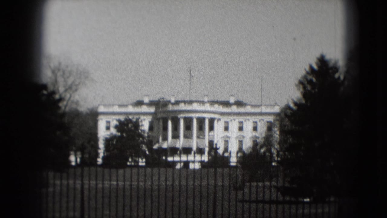 White House exterior seen beyond an iron fence, framed by trees and dark vignette edges.