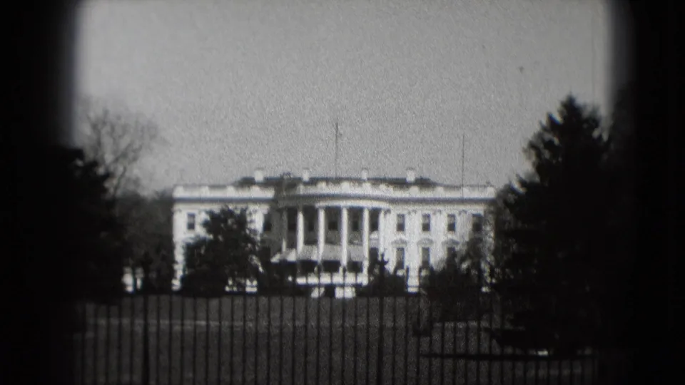 1975 8mm view of the White House in Washington, DC, seen from outside the fence with trees and heavy dark vignetting.