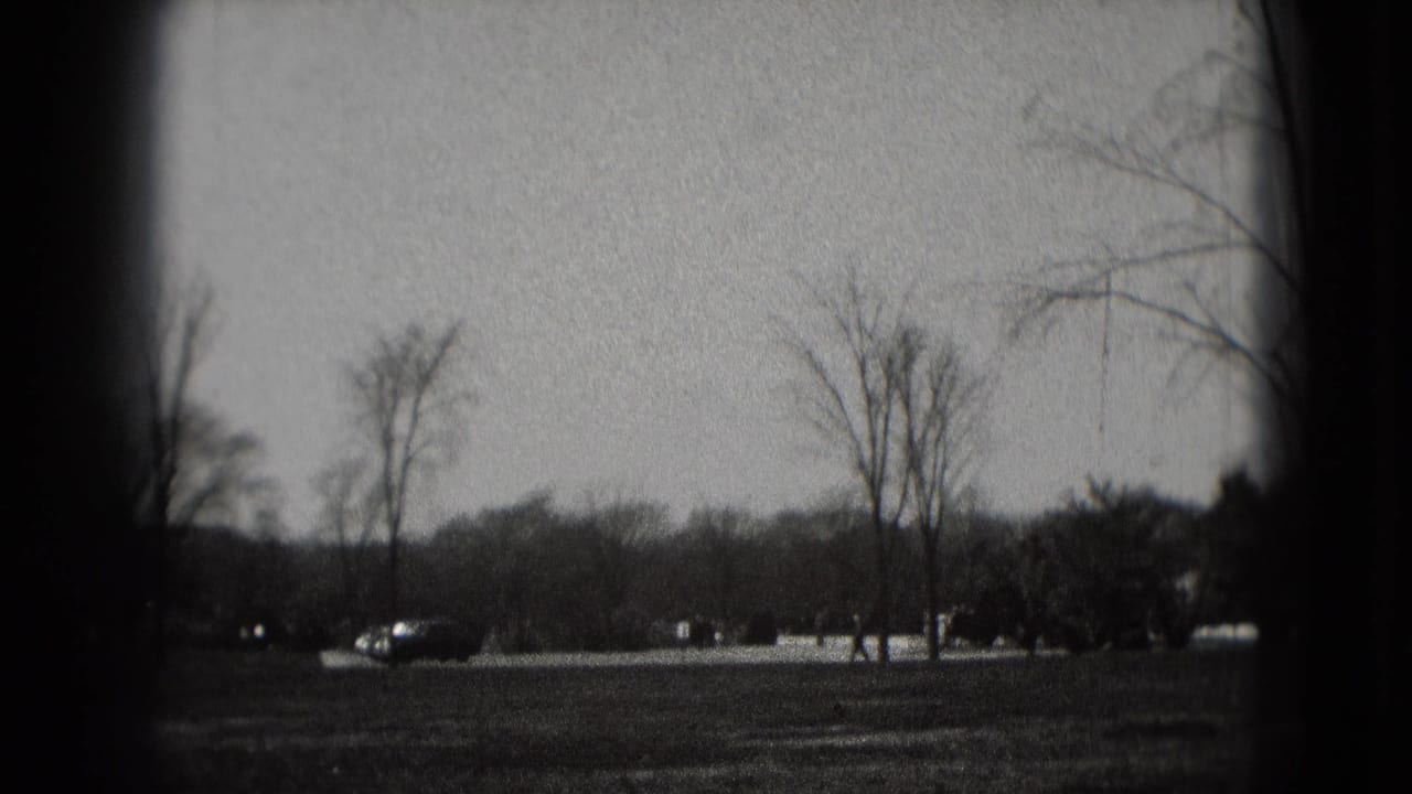 1975 Washington, DC home-movie view across parkland with bare trees, roadway, and distant cars before the memorial appears.