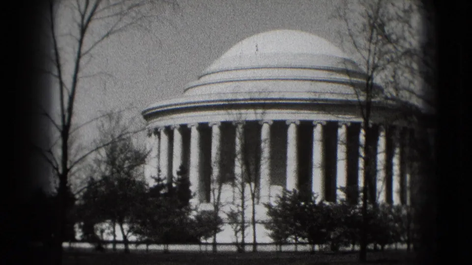 Washington, DC home-movie frame showing the Jefferson Memorial dome and colonnade behind trees and shrubs in 1975.