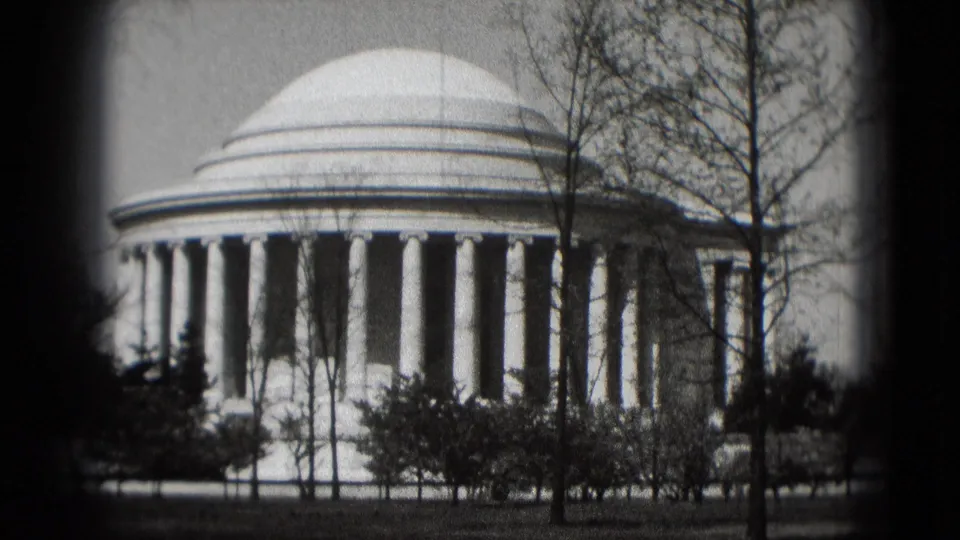 Black-and-white 8mm frame of the Jefferson Memorial in Washington, DC, showing the dome, colonnade, trees, and foreground plantings.