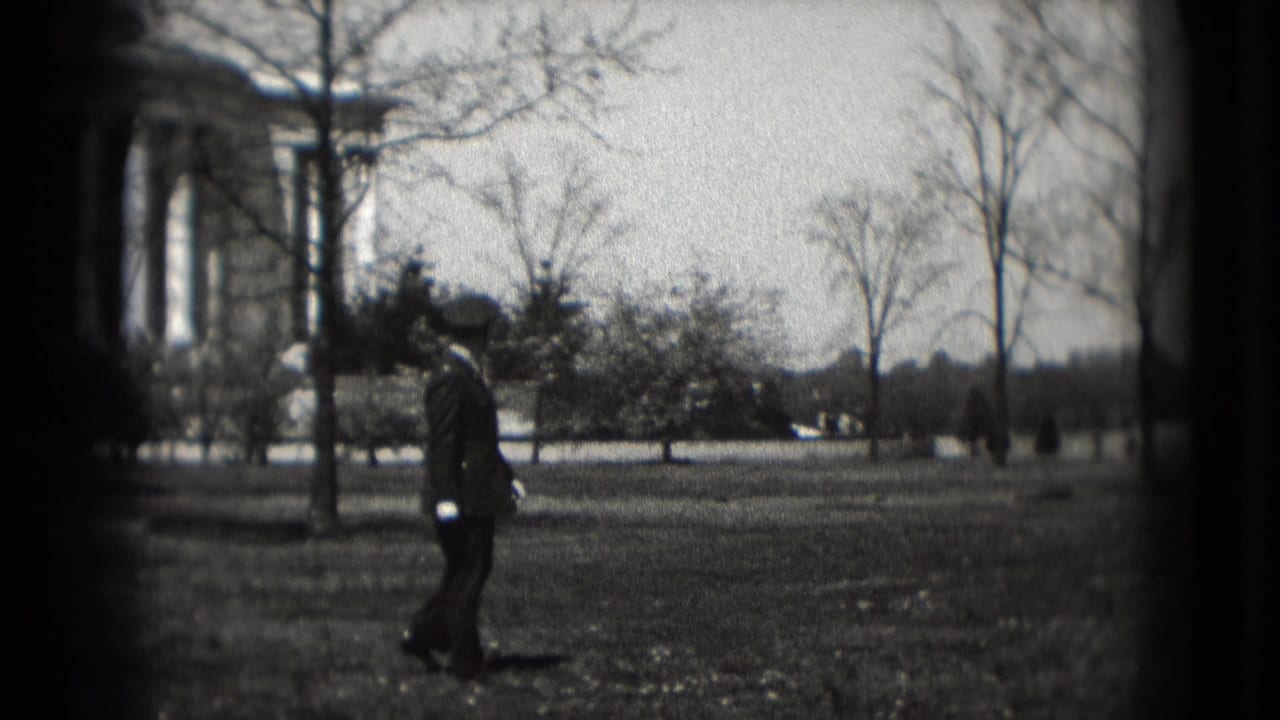 In 1975 Washington DC, a uniformed man walks across a grassy area with the Lincoln Memorial partly visible behind bare trees.