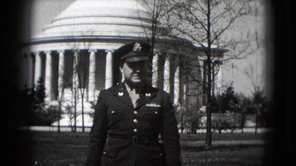 In 1975 Washington, DC, a uniformed adult man poses in front of the Jefferson Memorial dome and columns on black-and-white 8mm film.