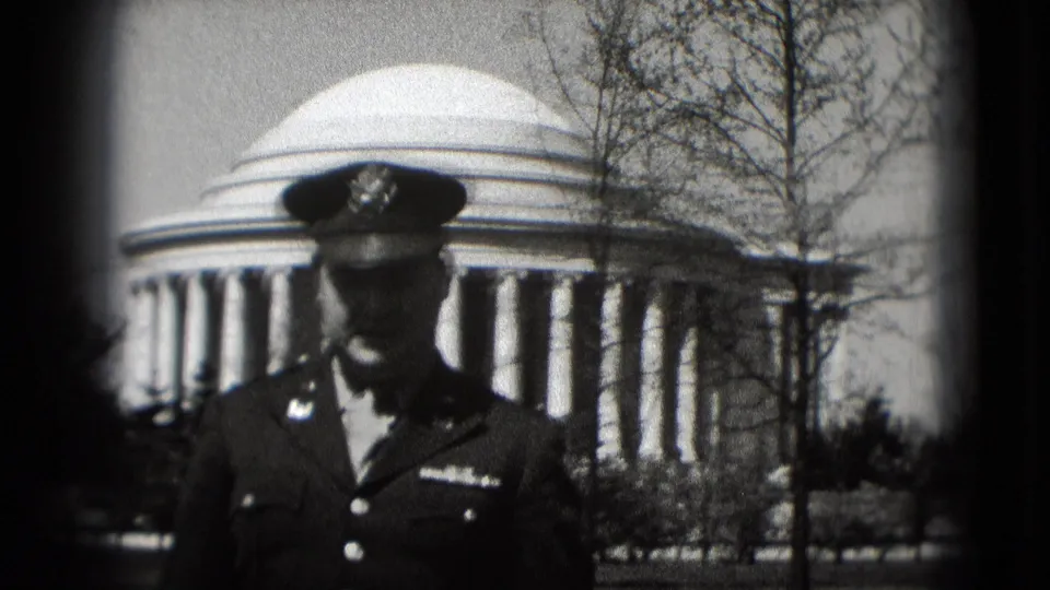 A closer 1975 Washington, DC frame shows a military-uniformed man before the Jefferson Memorial, partly shaded by his cap.