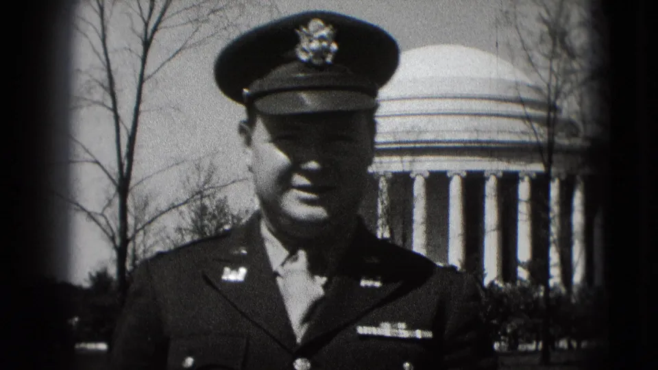 Close black-and-white 8mm view of a uniformed adult man at the Jefferson Memorial in Washington, DC, with bare trees and columns visible.