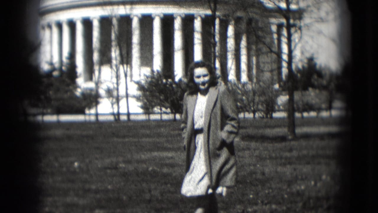 Smiling woman walking across grass with a domed columned building behind her.