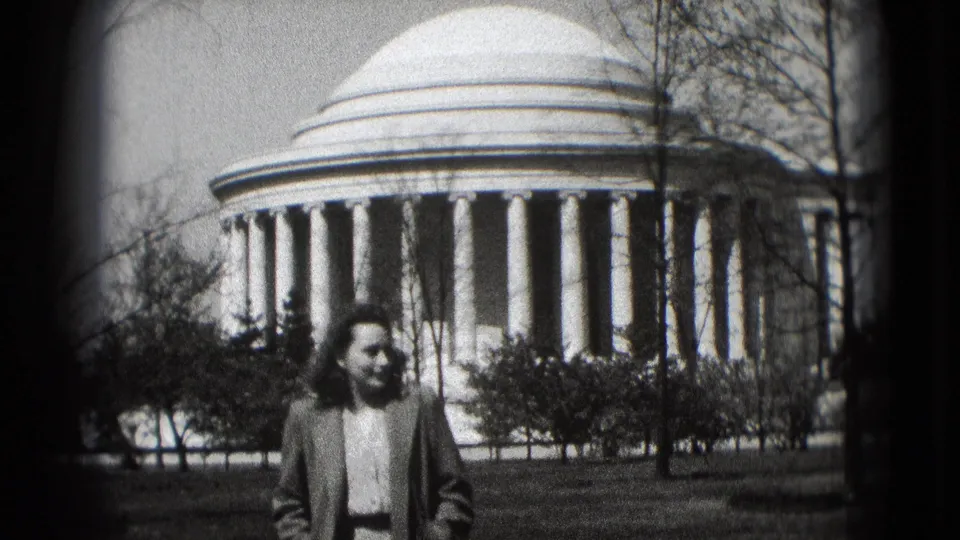 1975 Washington, DC frame with the woman low in the foreground, looking aside beneath the large white dome and columns.
