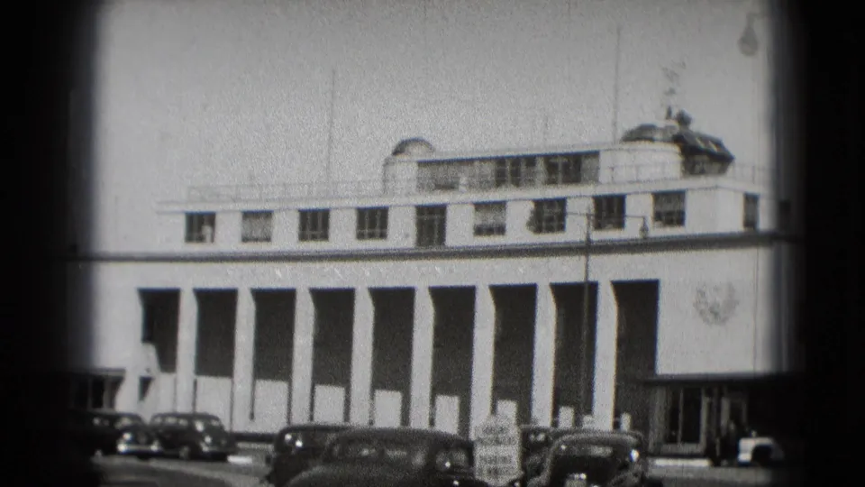 1975 Washington DC frame with a white columned facade, rooftop details, street signs, and older cars in the foreground.