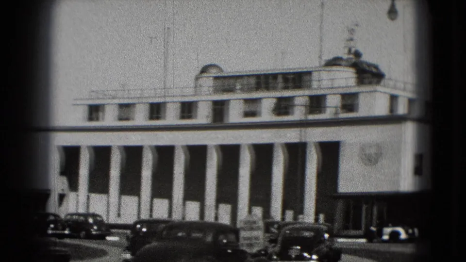 Washington DC 8mm frame from 1975 showing the columned building front, older parked cars, and soft home-movie focus.