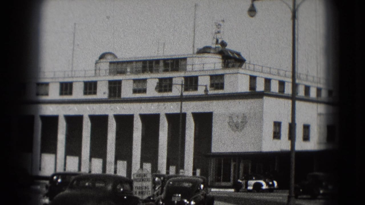 Washington DC airport terminal view on 8mm film, with columned facade, parked older cars, and a vehicle near the entrance.