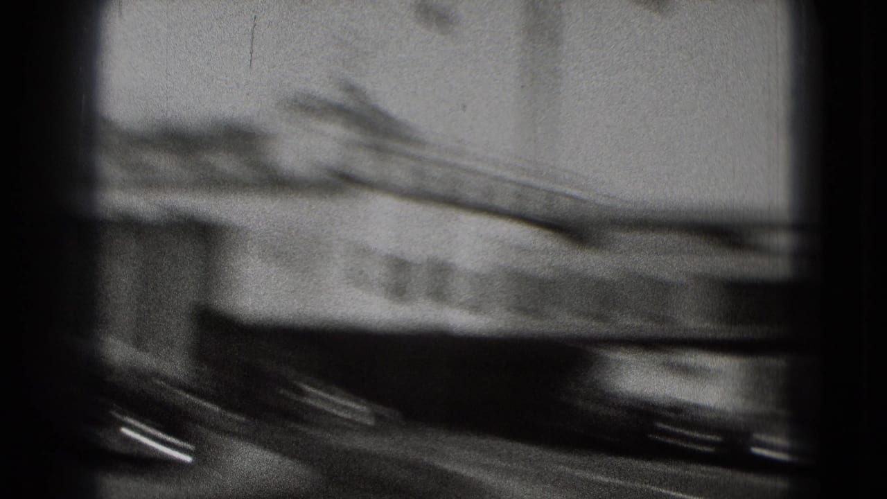 Motion-blurred Washington DC airport view from 1975 footage, showing a passing vehicle and indistinct terminal-side structure.