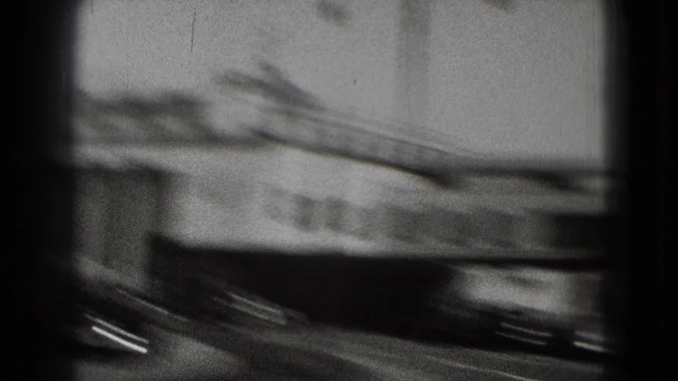 Motion-blurred Washington DC airport view from 1975 footage, showing a passing vehicle and indistinct terminal-side structure.