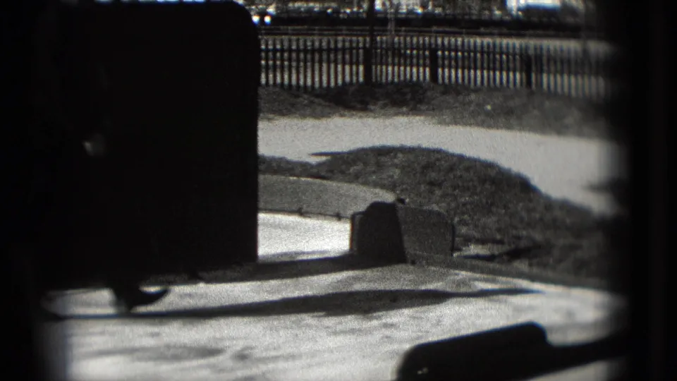 1975 Washington, DC 8mm frame showing a paved mini-golf course area through dark edges, with railing, low barriers, and open space beyond.