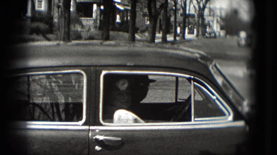 1975 Washington, DC home-movie view of a sedan side window with a passenger inside and homes behind.