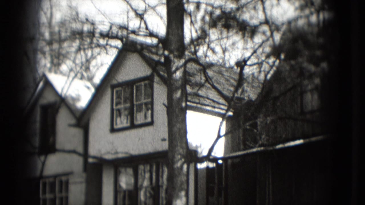 Residential houses and bare trees seen from a soft black-and-white 8mm frame.