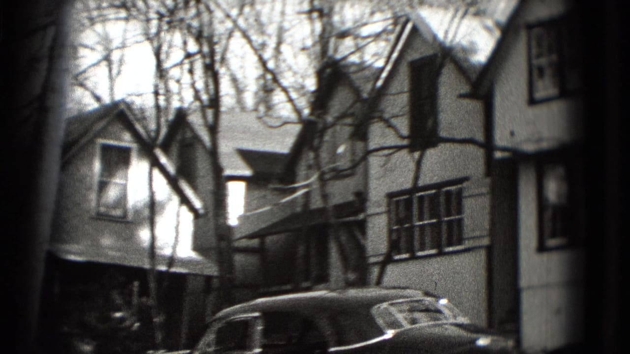 Detached houses beside bare trees with an older car partly visible near the curb.