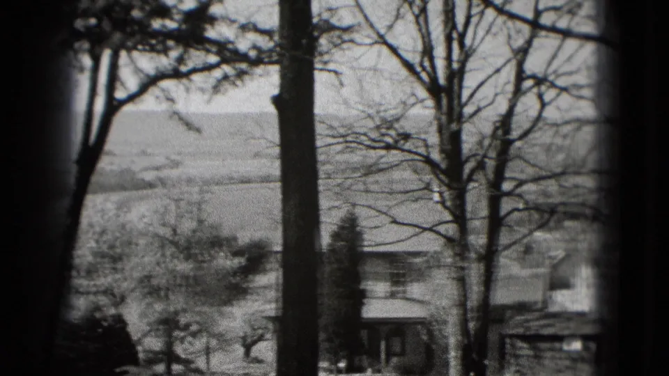 Black-and-white 8mm view near Washington, DC, with leafless trees, utility poles, open fields, and a small structure at the lower edge.