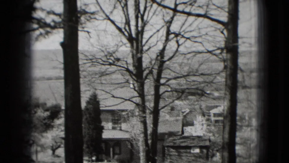 1975 8mm view from the Washington DC visit reel, looking past bare trees toward houses, open fields, and distant hills.