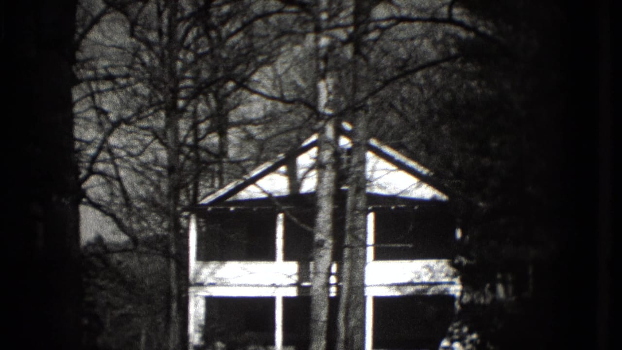 1975 Washington, DC home-movie frame showing a porch-front house partly obscured by leafless trees.