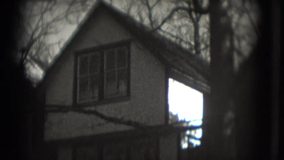 1975 Washington, DC 8mm frame showing a gabled house exterior with double upper windows and leafless branches across the view.