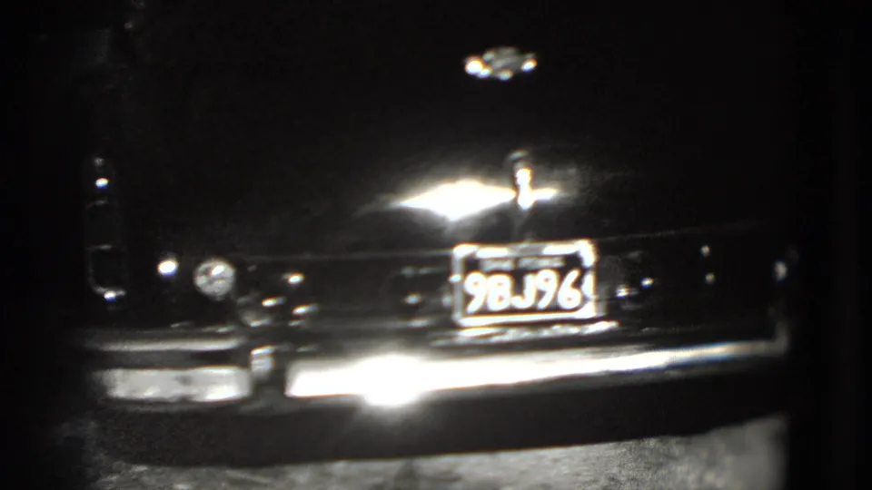 Close rear detail of a dark older sedan with chrome trim and a Pennsylvania license plate in 1975 home-movie footage.