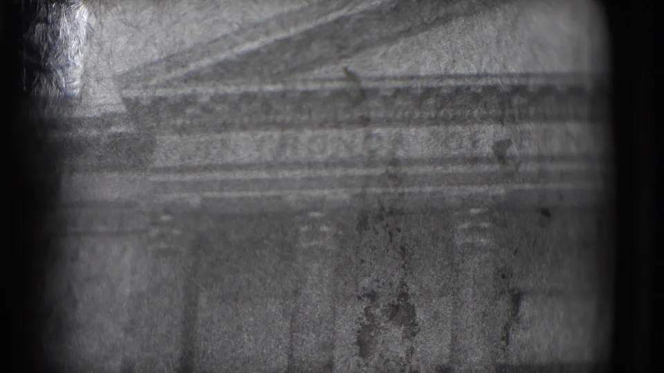 1975 8mm Washington DC view of a triangular pediment and classical stone facade, seen through heavy grain and handheld framing.