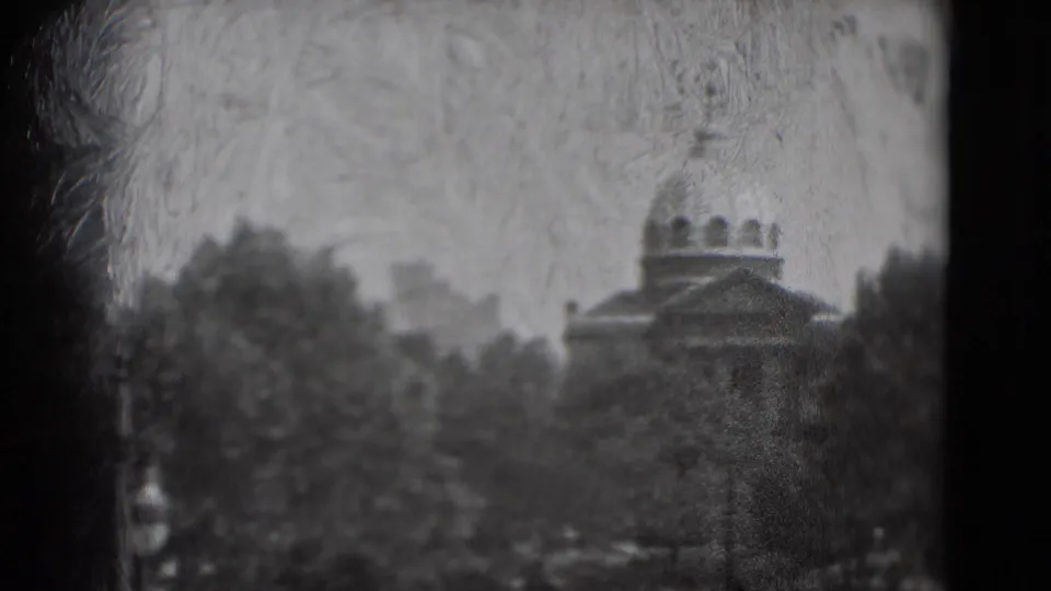 1975 8mm Washington, DC frame with the U.S. Capitol dome appearing beyond trees, viewed through a dark window frame.