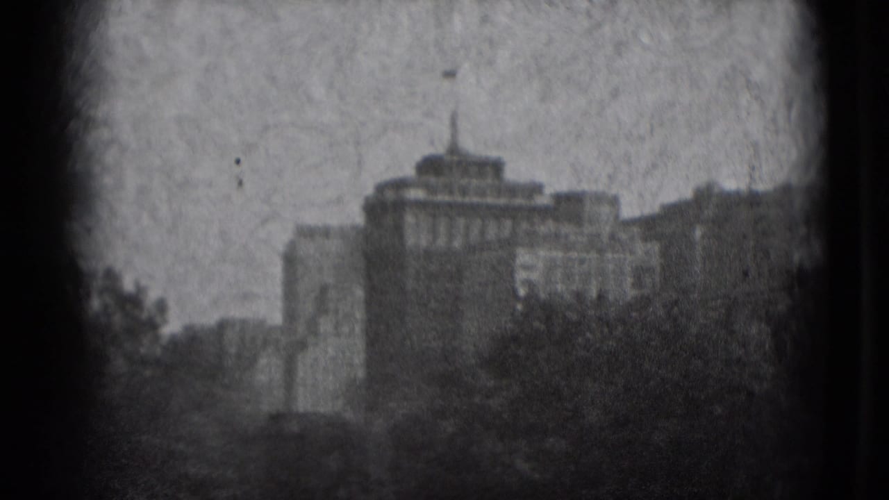 Distant hazy buildings and trees seen through dark frame edges.