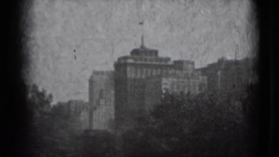 1975 Washington, DC home-movie frame showing distant buildings, tree cover, haze, grain, and heavy vignetting.