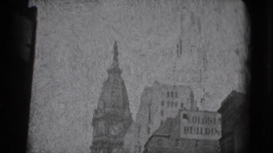 Black-and-white 1975 Washington DC frame showing a distant domed or spired building, urban structures, and a partial BUILDING sign.