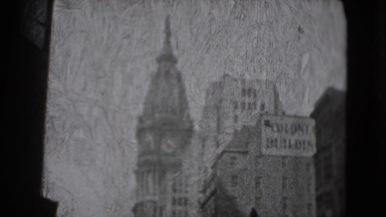 Grainy street view with a tower, tall buildings, and a partially visible Colonie Building sign.