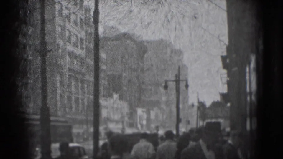 1975 Washington, DC street view with pedestrians, older vehicles, streetlamps, and downtown building facades.