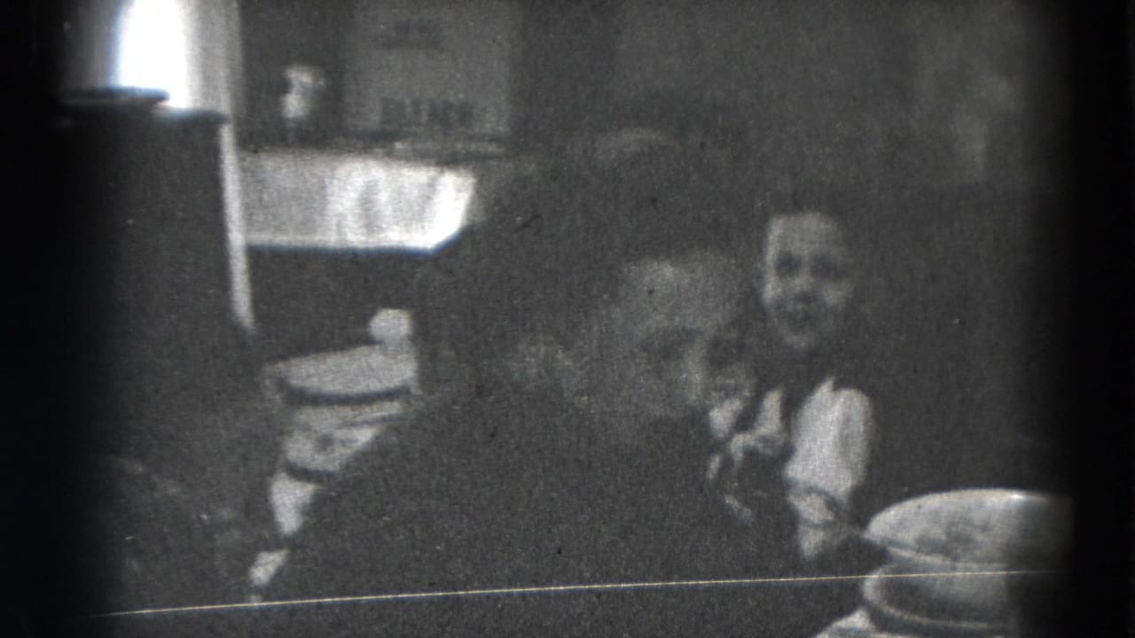 Two people seated at a dim dining table with plates and serving dishes.