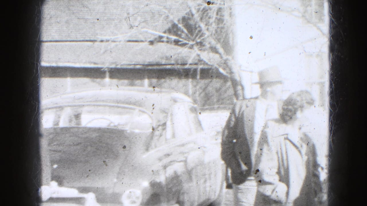 In Lincoln, Nebraska home-movie footage from 1947, adults in coats stand near a parked car outside a residential house.