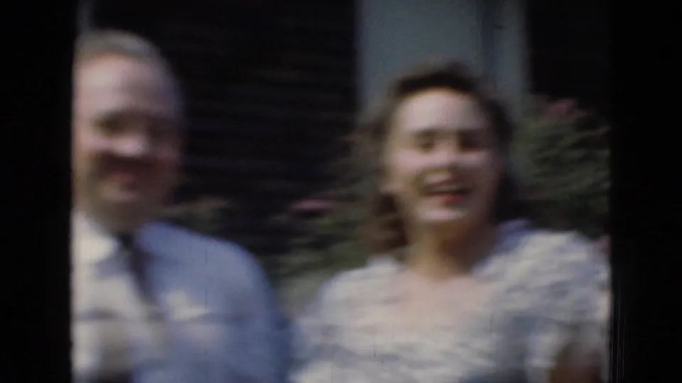 A soft, motion-blurred frame shows the same adults smiling outdoors, with garden foliage behind them.