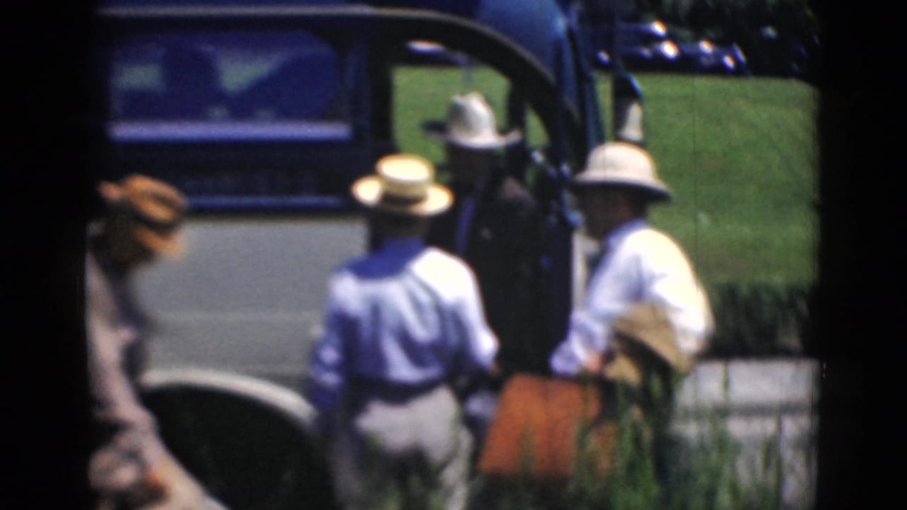 Adult men in light clothing and hats gather at the open bus door in Middletown, Pennsylvania, as captured on 8mm film.