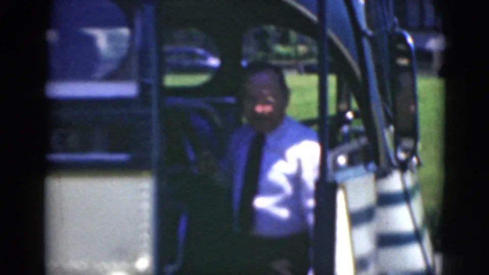 In Middletown, Pennsylvania, a man in a light shirt and tie appears near an antique bus doorway in a soft 8mm frame.