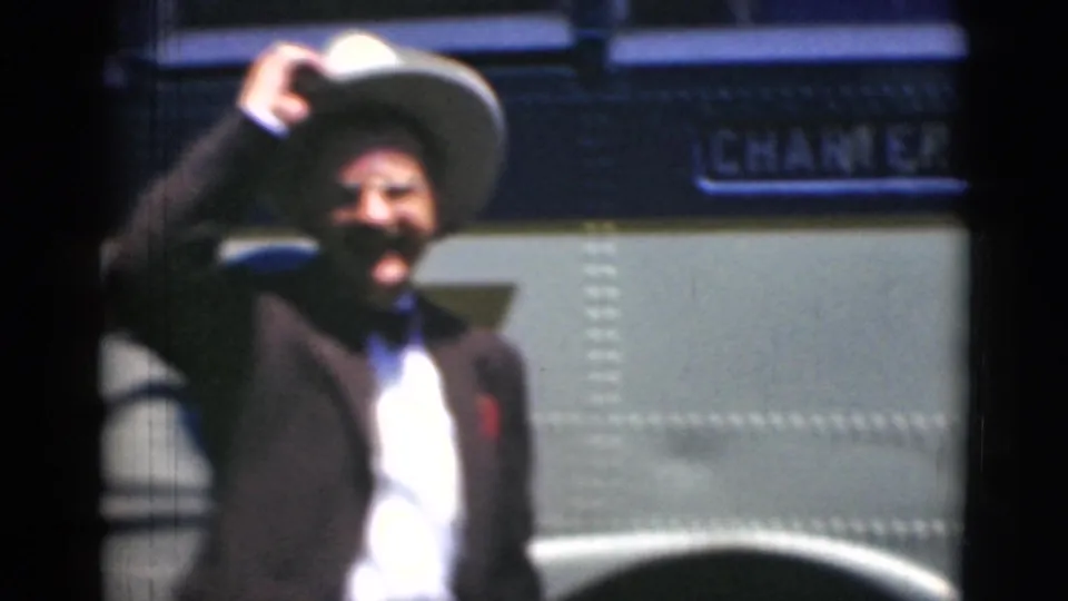 In Middletown, Pennsylvania archival 8mm footage, a suited man in a white hat smiles and waves beside a charter bus.