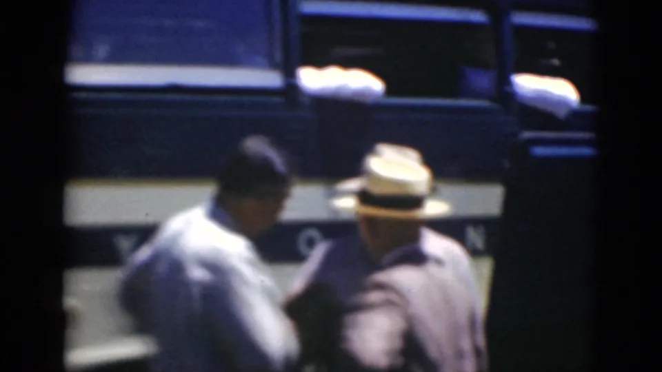 In Middletown, Pennsylvania, adult men in shirts and brimmed hats stand near the side of a dark bus in 1947 home-movie footage.