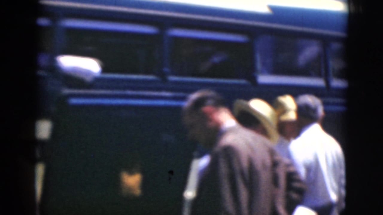 Several men stand near a bus door or side panel, partly obscured by frame divisions.