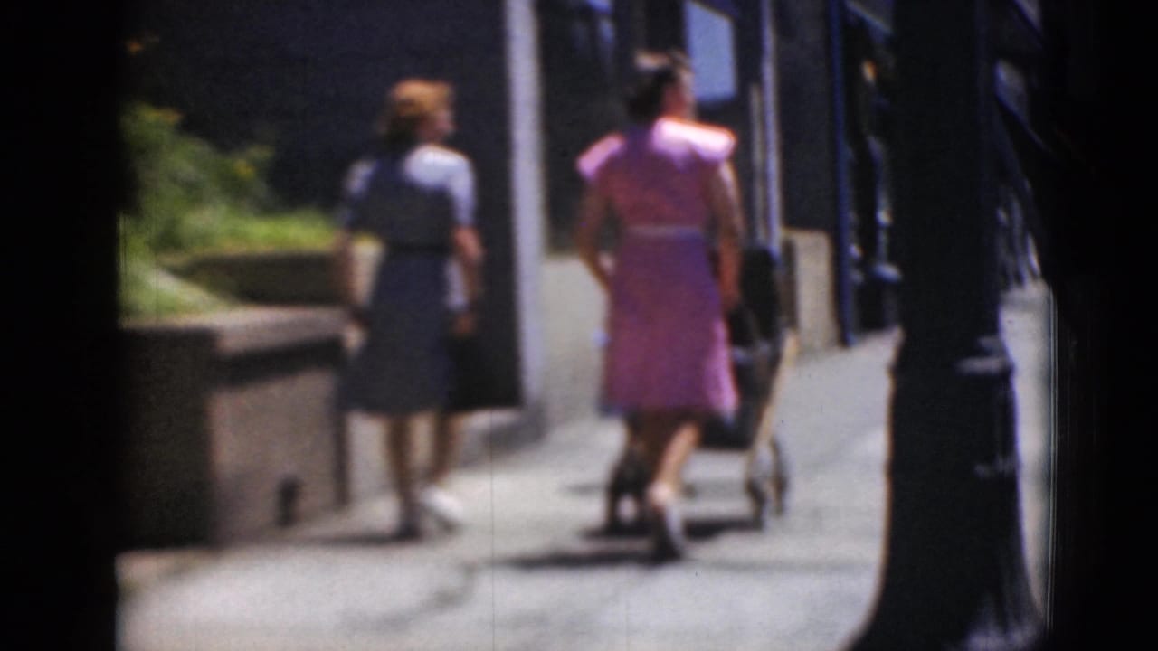 The women continue walking away on a sunlit sidewalk in Middletown, Pennsylvania, with a stroller visible near the right side.