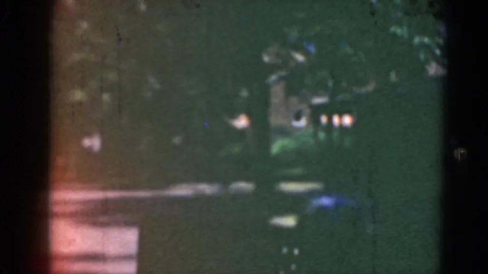 A shaded residential street in Middletown, Pennsylvania, appears through grainy 8mm film, with trees, houses, lawns, and a dark vehicle shape.