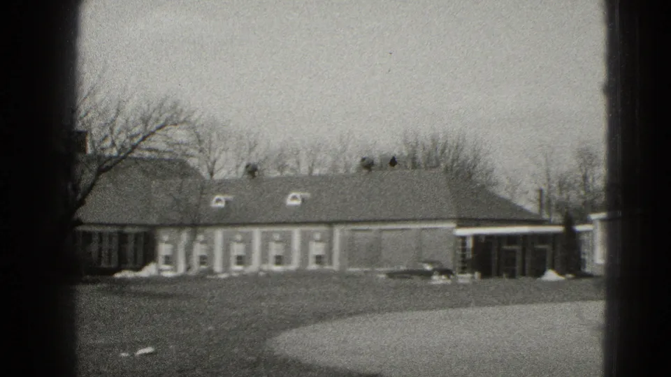Middletown, Pennsylvania 8mm frame showing a low brick building, bare trees, lawn, walkway, and parked car.